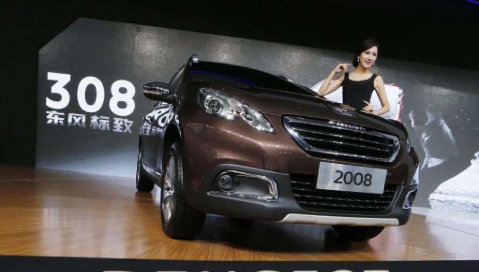 A model poses beside the Peugeot 2008 at the Guangzhou 2013 Auto Show